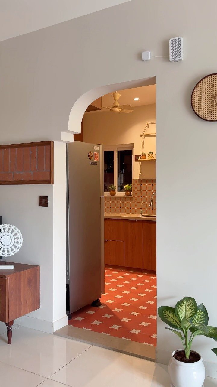 Reddish-brown patterned floor tiles in a kitchen viewed through an arched doorway.