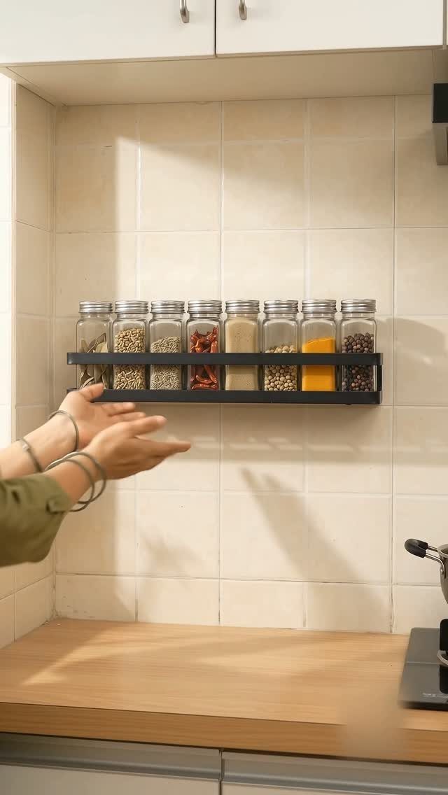 Spice rack with glass jars on a beige tiled kitchen wall.