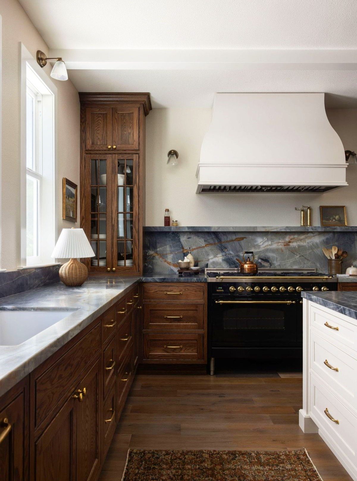 Kitchen with dark wood cabinets, gold hardware, and a blue marbled backsplash.