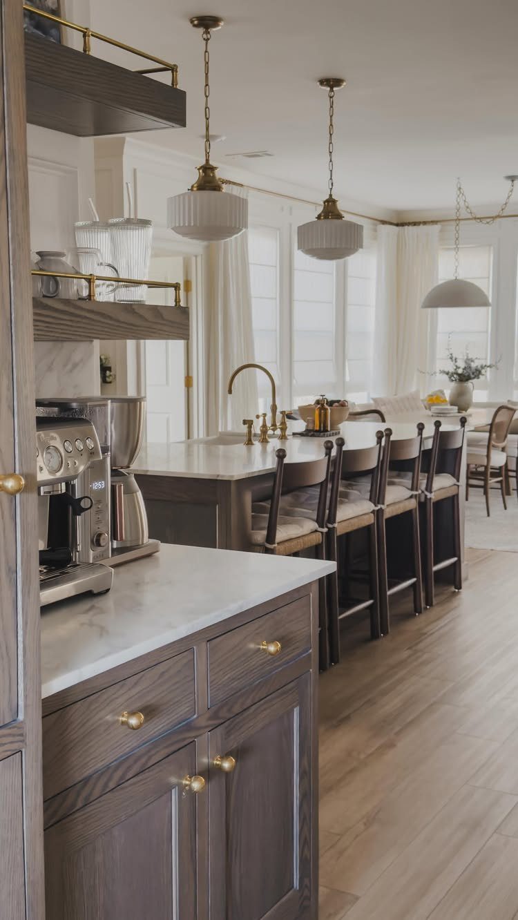 Grey-brown wooden kitchen cabinets with white marble countertops and a large central island.