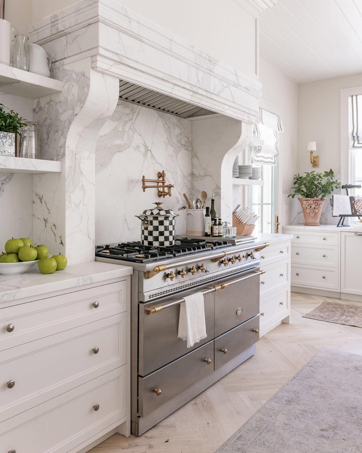 Ornate white marble range hood surround over a professional stainless steel kitchen stove.
