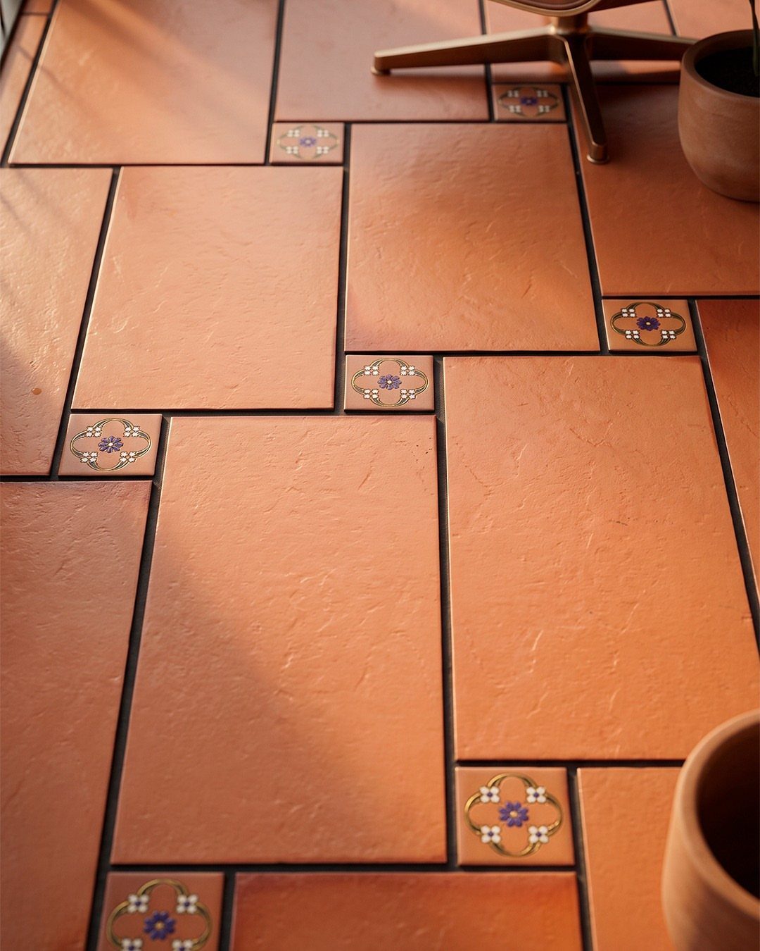 Terracotta tile floors with small decorative floral inserts in a rustic kitchen setting.