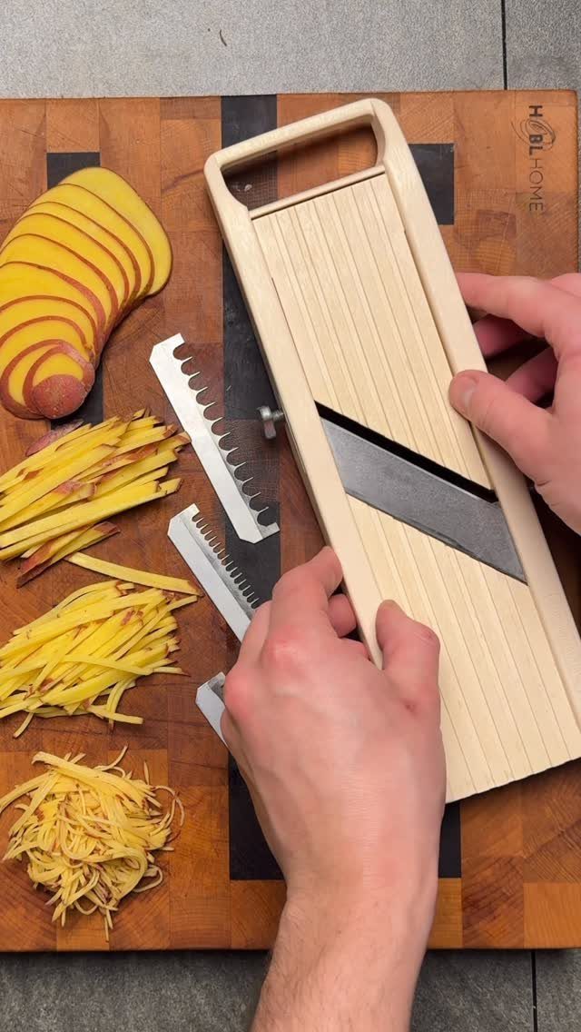 Wooden Japanese mandoline slicer on a cutting board with sliced yellow vegetables.