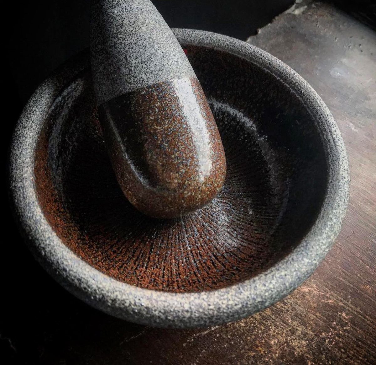 Stone suribachi mortar with ridged interior and a matching stone pestle.
