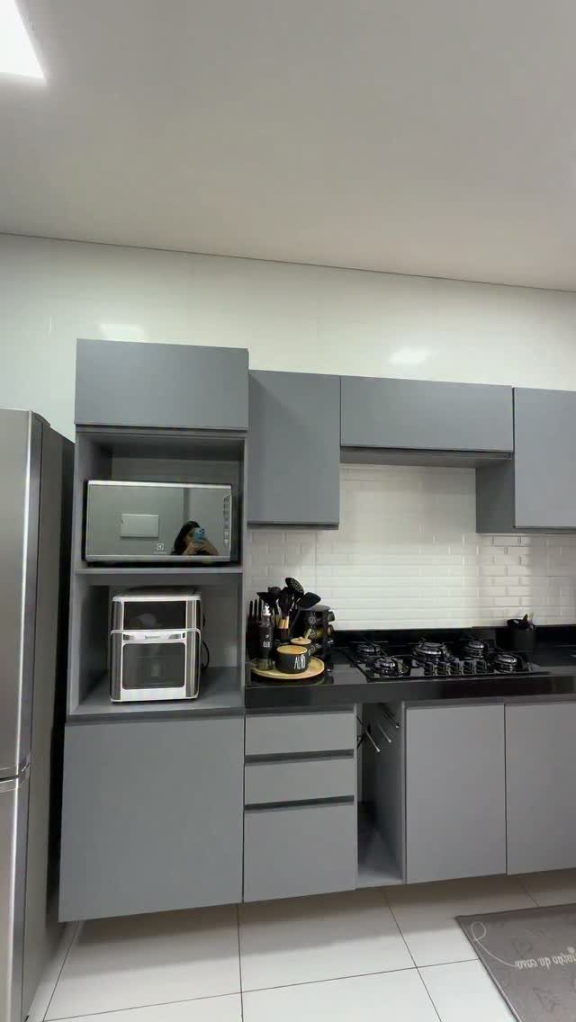 Gray kitchen cabinets with a black countertop and white tiled backsplash.