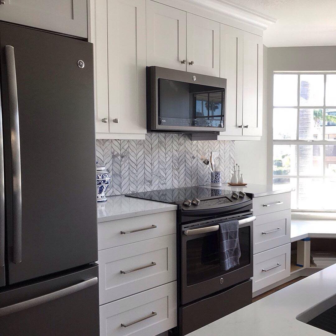 White kitchen cabinets with dark gray refrigerator and oven as central focal points.