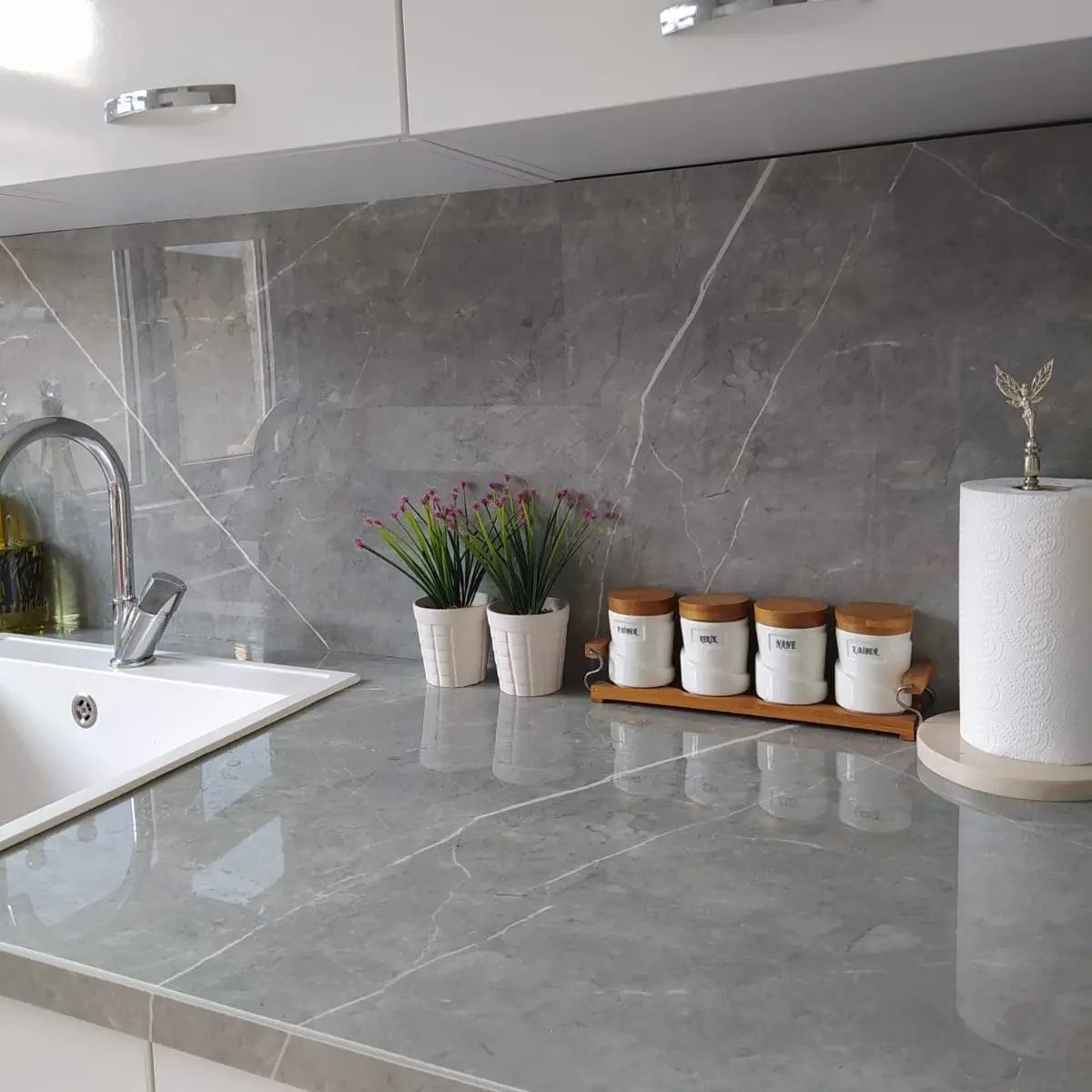 White kitchen cabinets with gray marbled countertops and a matching gray backsplash.