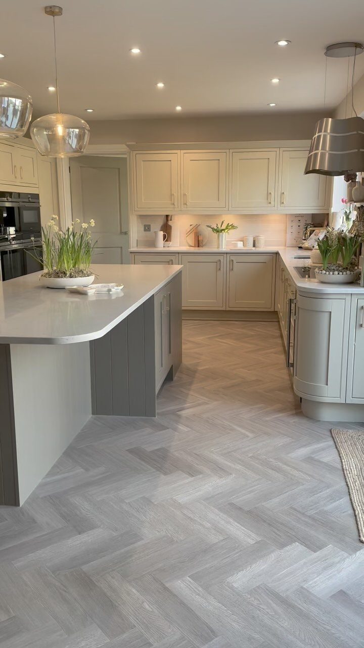 Kitchen with off-white cabinets, a gray island, and light gray herringbone flooring.