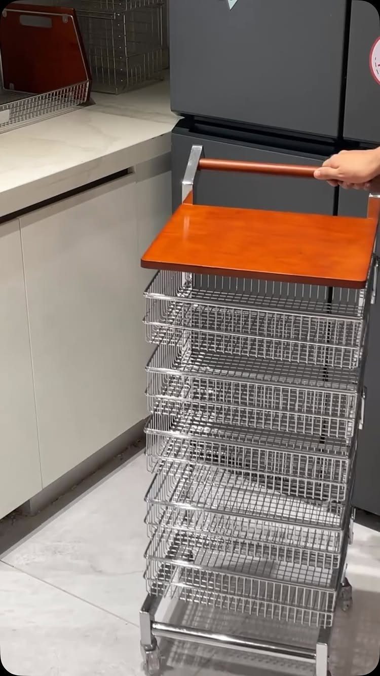 Slim rolling storage cart with wooden top and multiple chrome wire baskets in kitchen.