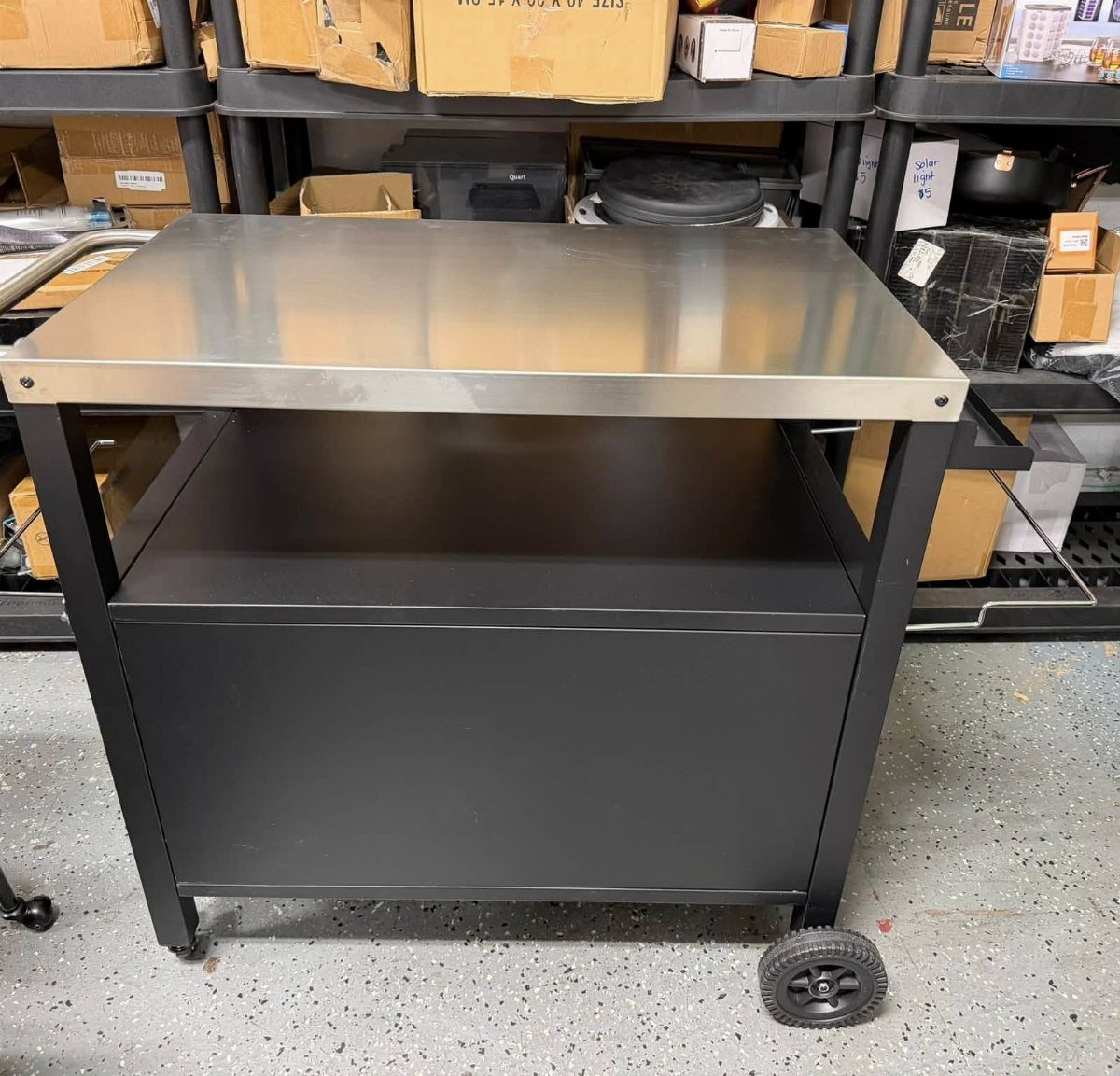 Black kitchen cart with a stainless-steel top surface in a storage room.