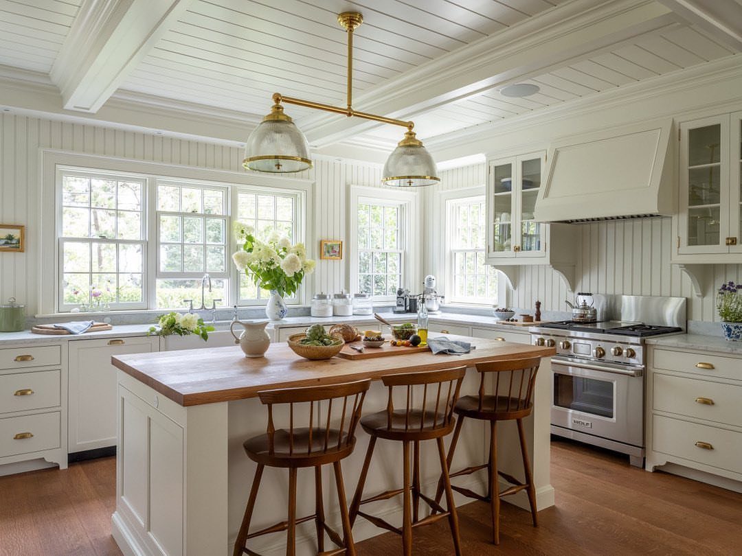 White beadboard walls and ceiling in a bright cottage kitchen with wooden island.