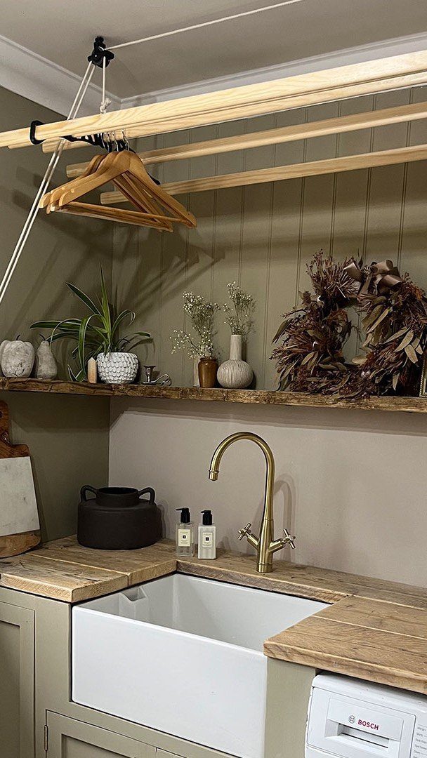 Ceiling-mounted wooden clothes drying rack above a farmhouse sink with butcher block countertops.