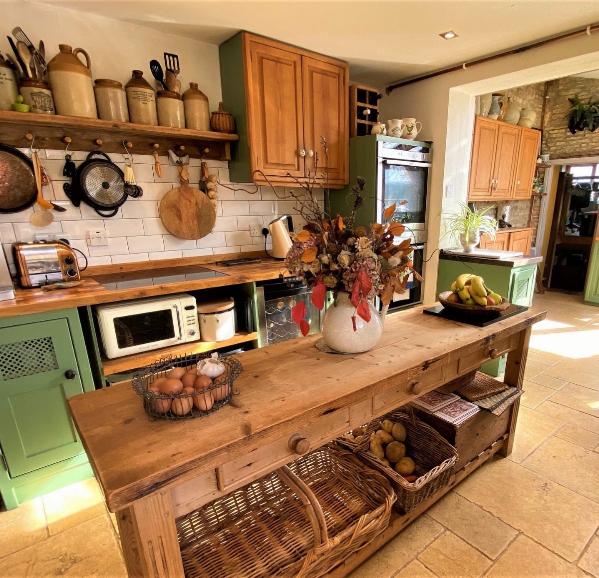 Wooden freestanding kitchen island with wicker baskets in a rustic cottage kitchen.