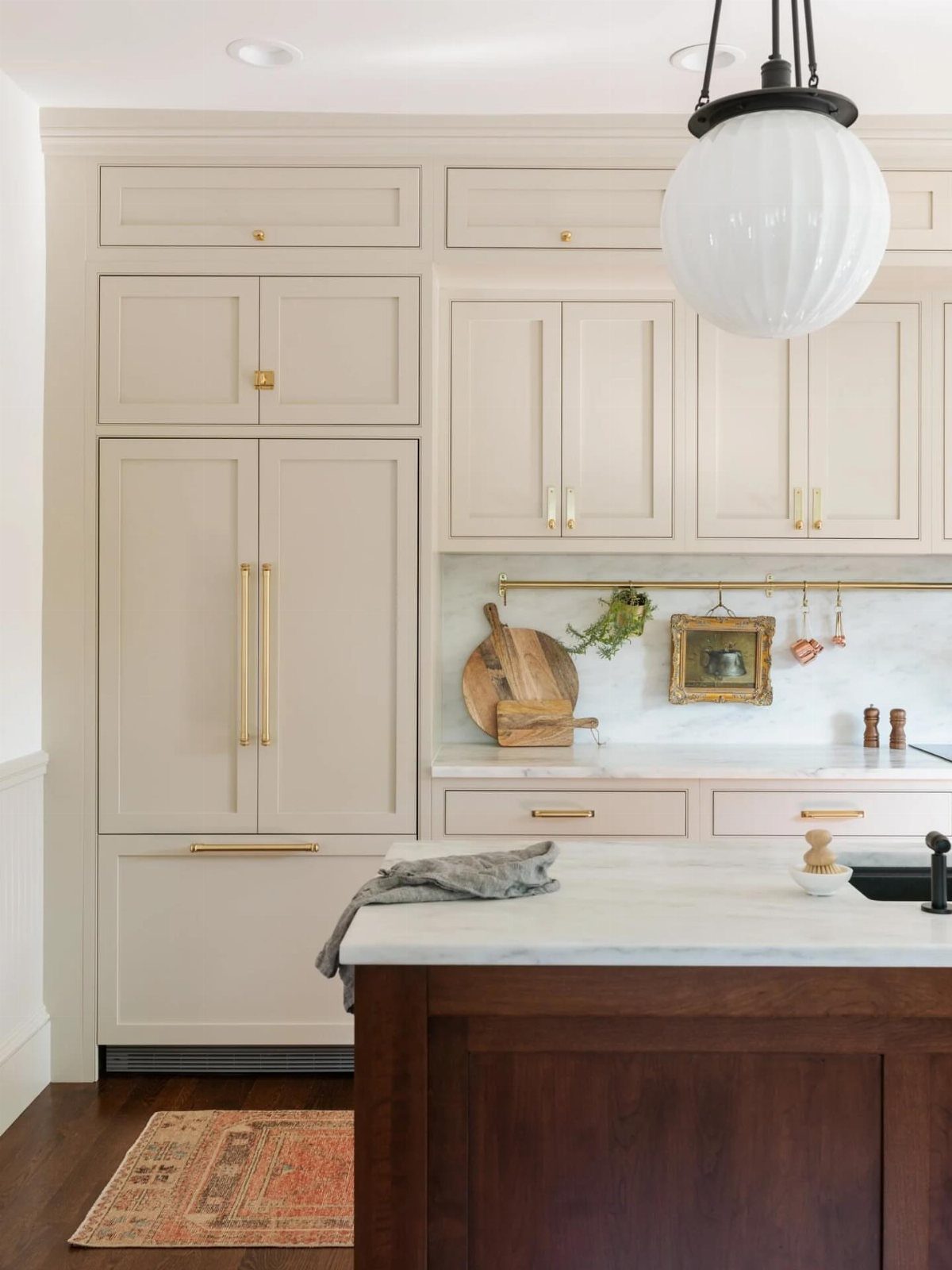 Cream painted shaker cabinets with gold handles in a bright cottage style kitchen