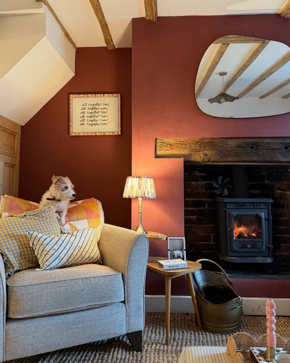 Cozy living room with burgundy walls, a wood-burning stove, and a gray armchair.