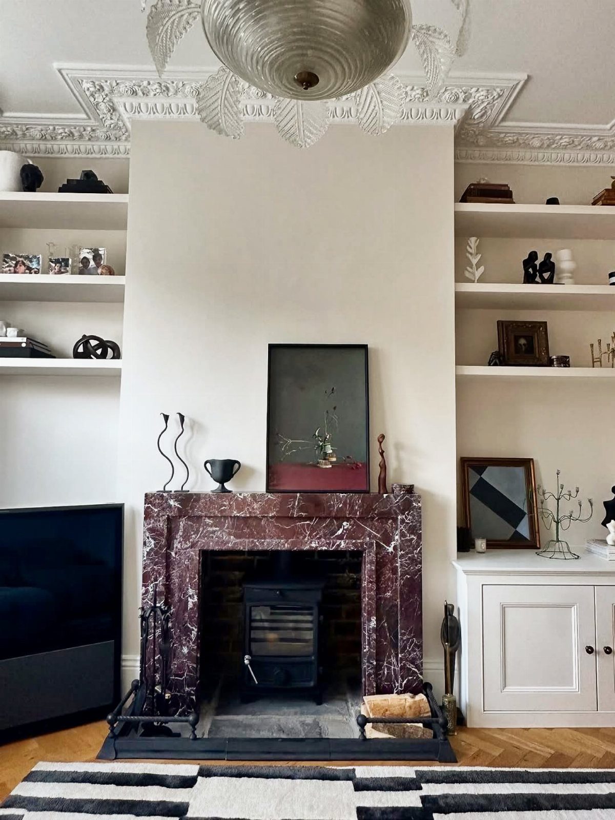 Burgundy marble fireplace surround with a black stove in a white living room.