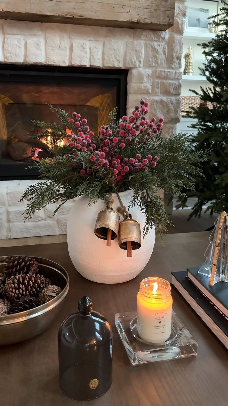 Burgundy berries and greenery in a white vase on a wooden table.