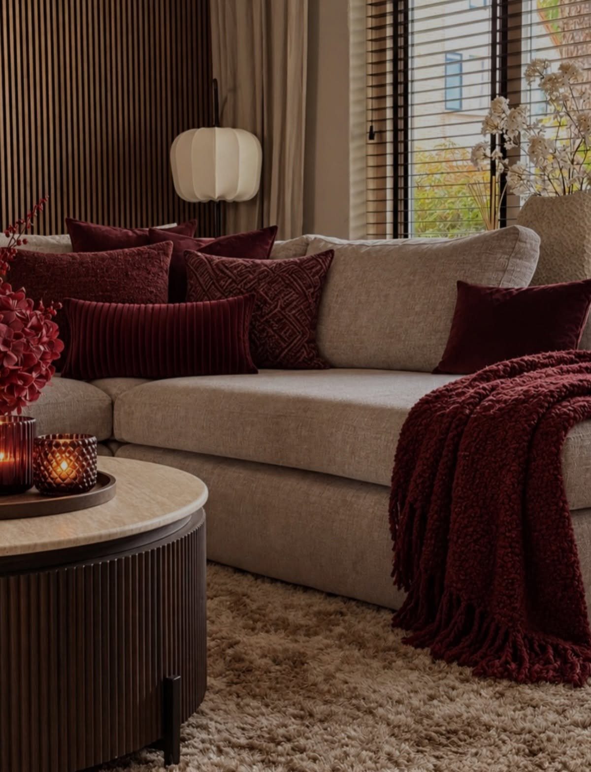 Gray fabric sofa with burgundy accent pillows and a burgundy throw blanket.