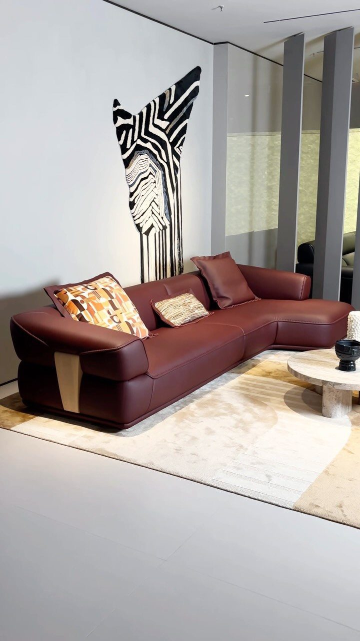 Burgundy leather sectional sofa with decorative pillows in a modern white living room