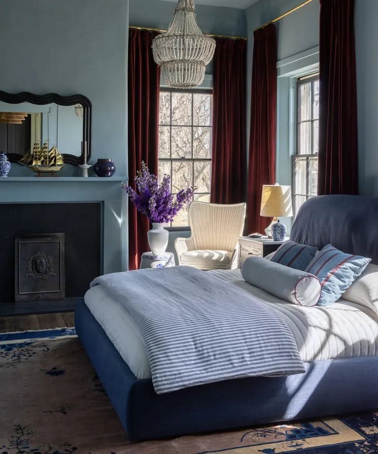 Burgundy velvet curtains and navy blue bedding in a bedroom with light blue walls.