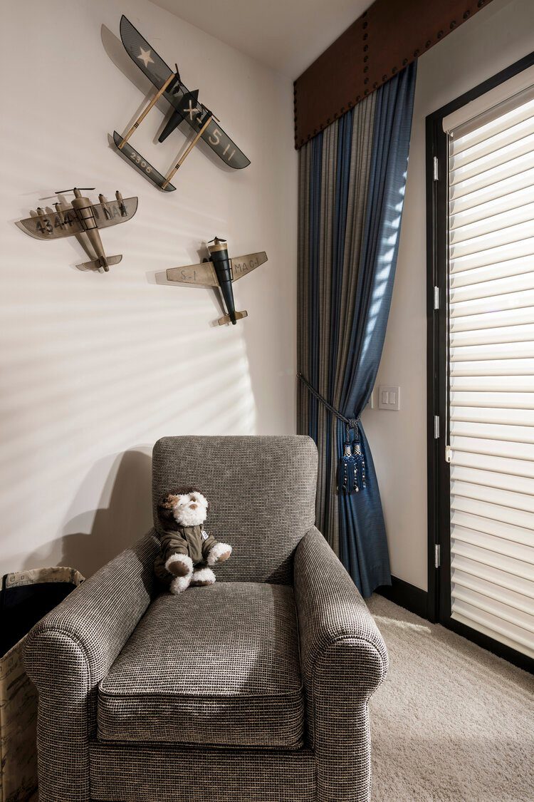 Navy blue striped curtains and model airplanes in a themed child's bedroom corner.