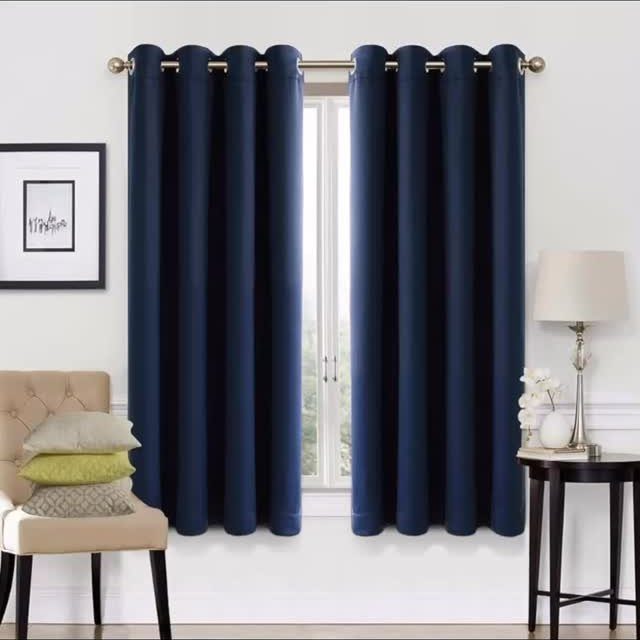 Navy blue curtains on a gold rod in a bright bedroom setting.