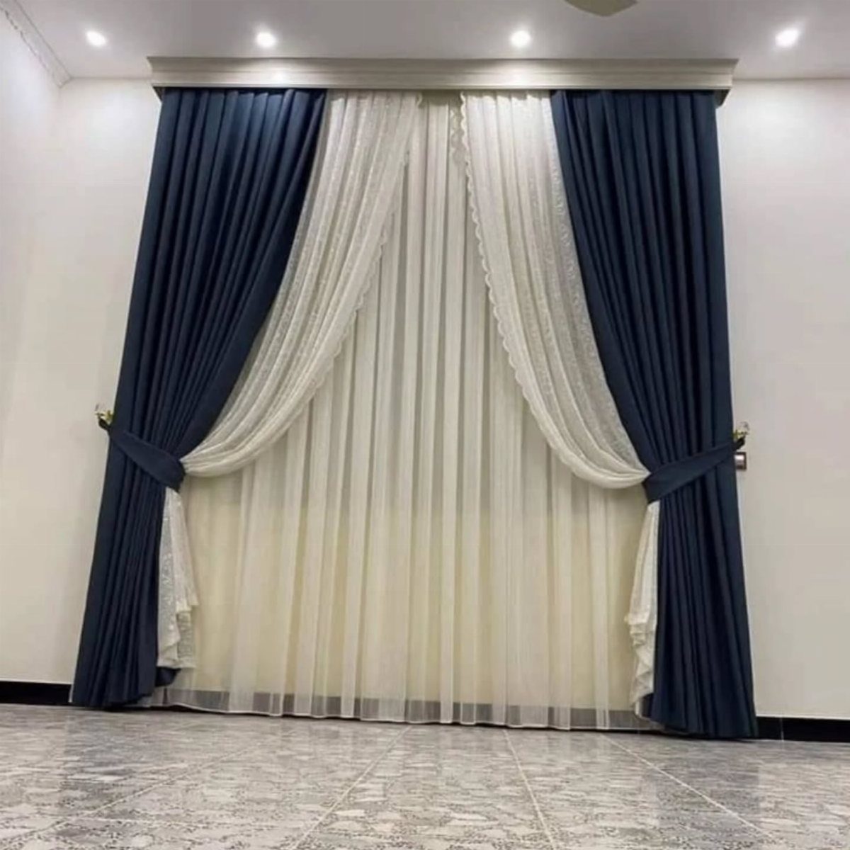 Navy blue velvet curtains layered over sheer white curtains in a bright room.