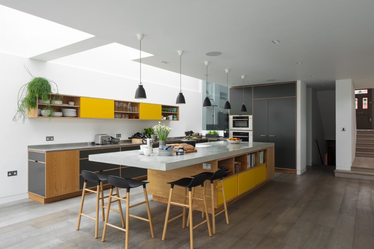 Modern kitchen island with a white countertop and black bar stools for breakfast seating.
