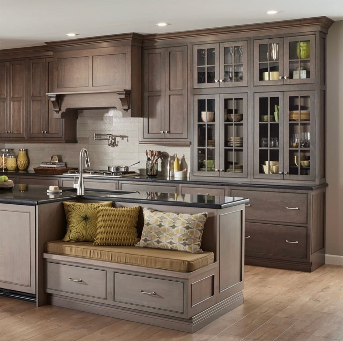 Grey wooden kitchen cabinets with a built-in breakfast nook and yellow accent pillows.