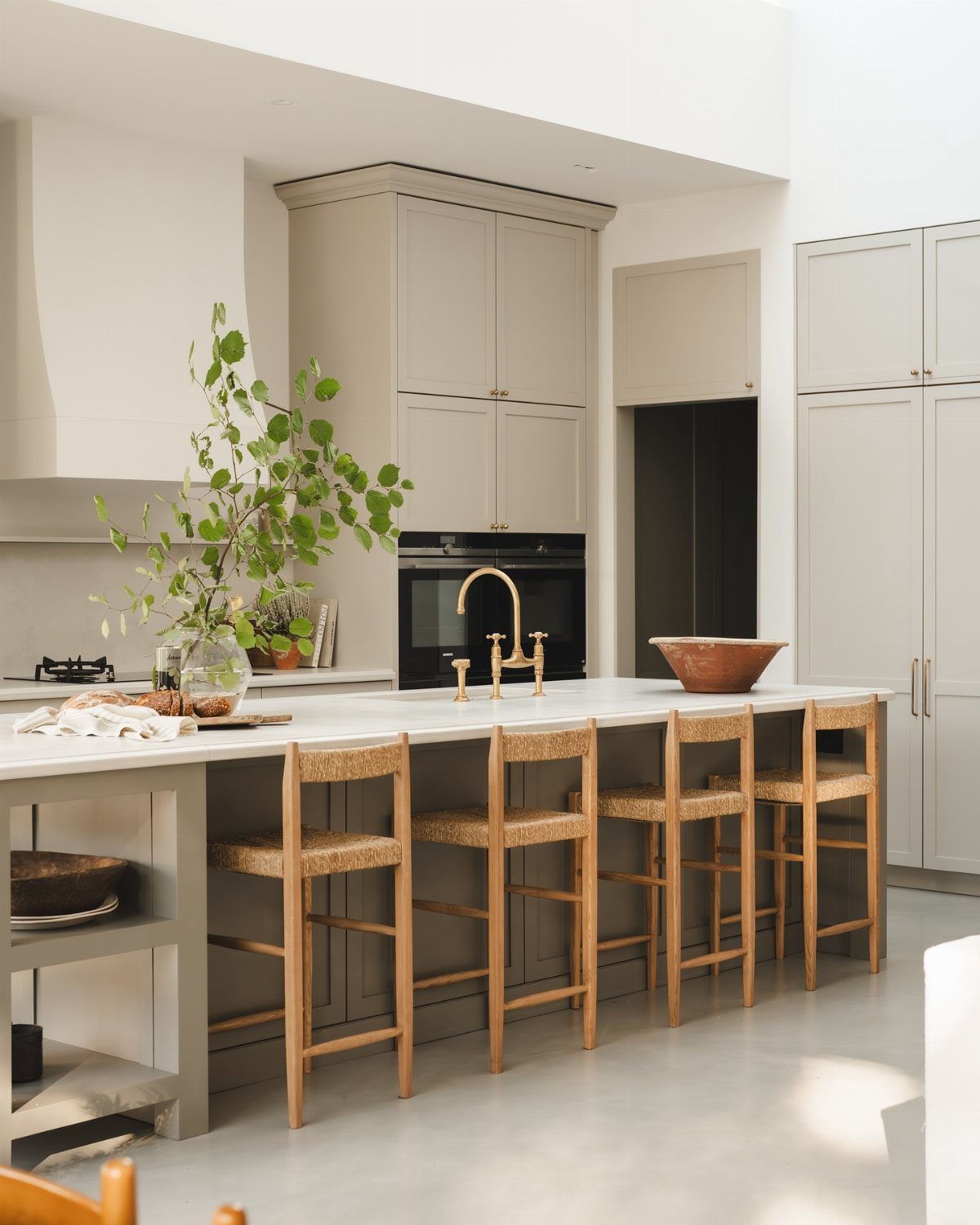 Kitchen island with wooden stools and light grey shaker style cabinets.