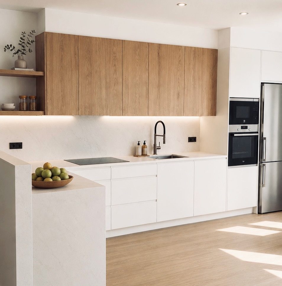 Modern kitchen with white slab cupboards and light wood upper cabinets.