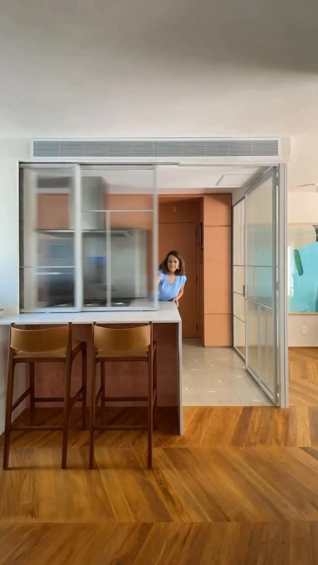 Frosted glass sliding doors partitioning a modern kitchen with leather bar stools and herringbone floors.