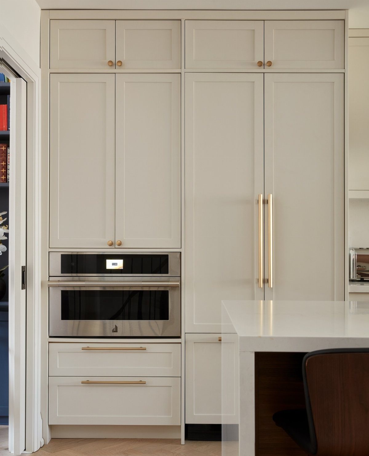 Full-height light grey shaker cabinets with gold hardware and a built-in oven.