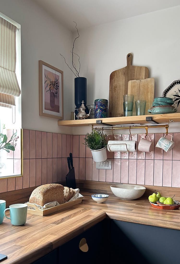 Pink tiled kitchen walls with dark lower cabinets and warm wood countertops.