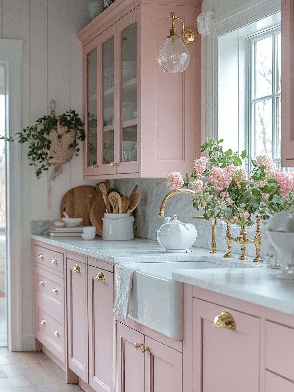 Salmon pink kitchen cabinets with white marble countertops and gold hardware accents.
