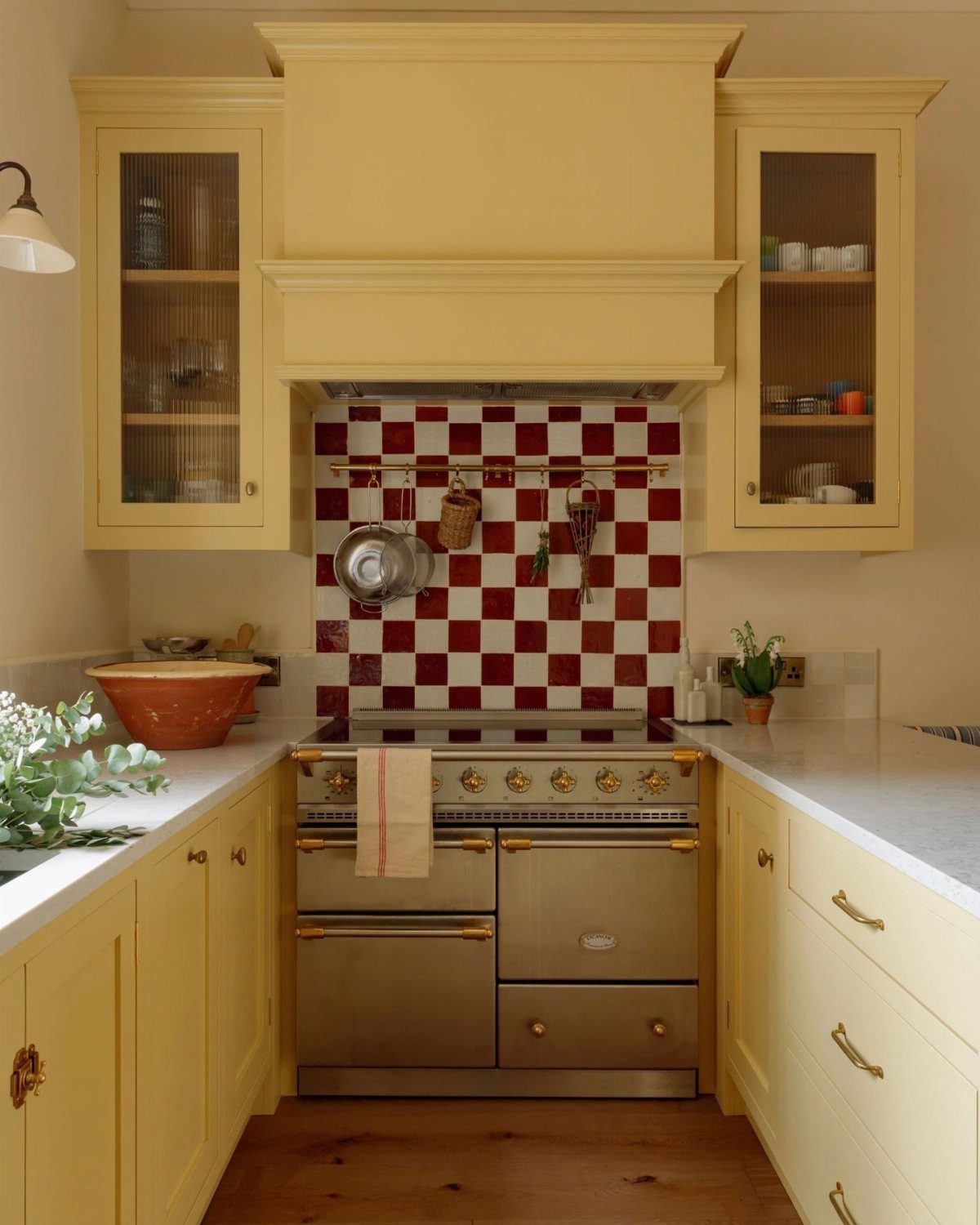 Pale yellow kitchen cabinets with a red and white checkered tile backsplash.