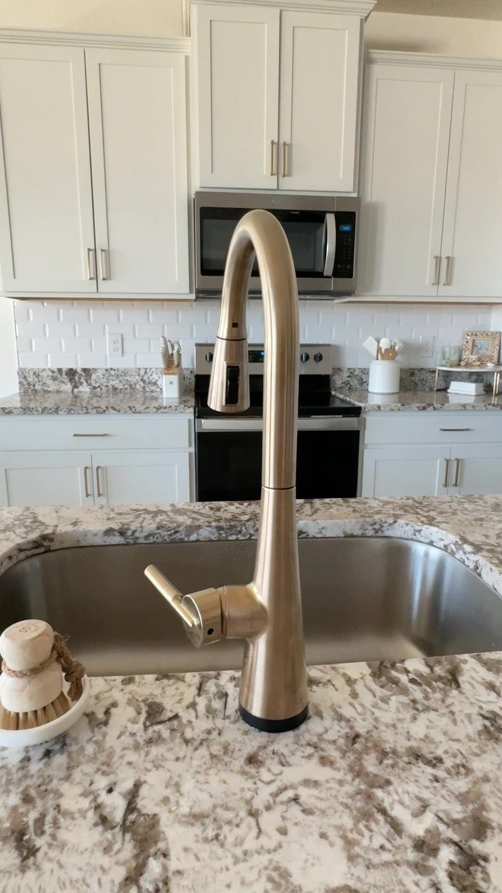 Bronze high-arc pull-down kitchen faucet installed on a granite countertop with stainless steel sink.