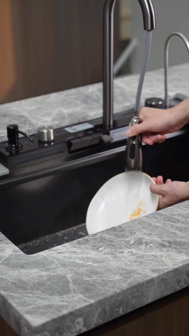 High-arc pull-down kitchen faucet rinsing a white plate in a black sink.
