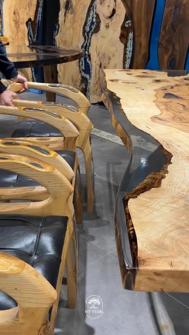 Natural wood table with a dark epoxy resin river and carved wooden chairs.