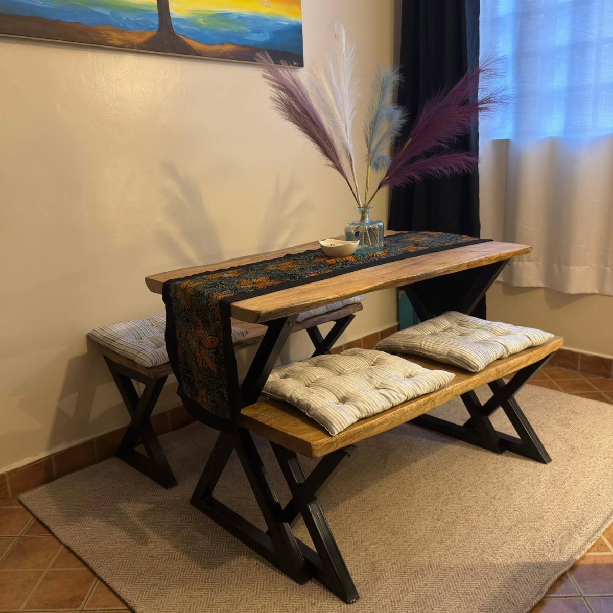 Wood dining table with black metal X-frame base and matching cushioned benches.