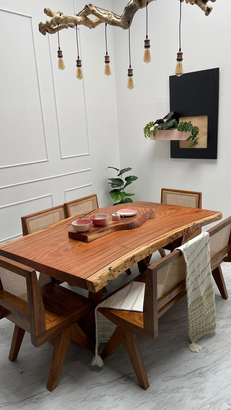 Live-edge wooden dining table with cane-back chairs and a branch light fixture.