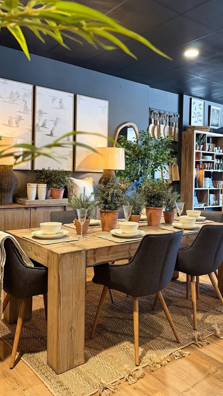 Weathered reclaimed wood dining table with dark grey chairs on a jute rug.