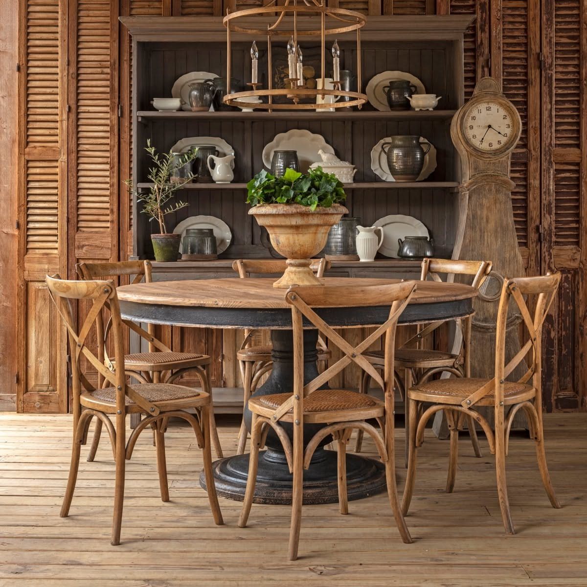Round farmhouse wood table with cross-back chairs in a rustic dining room