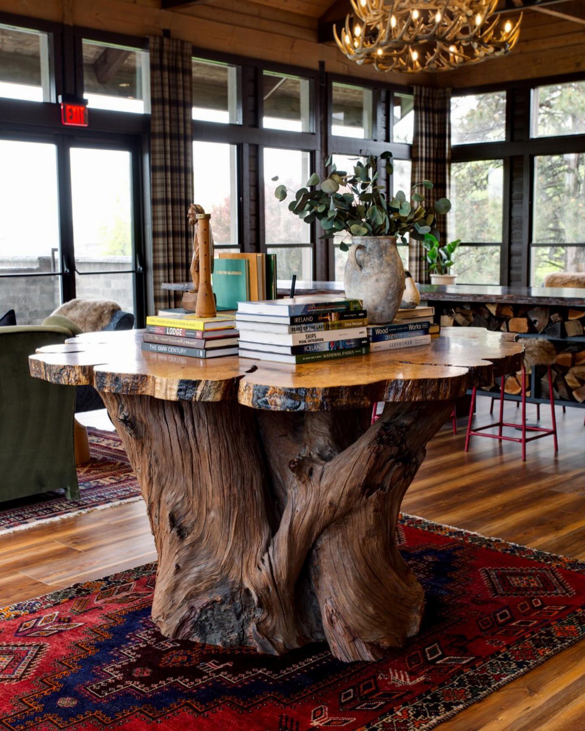Round natural wood table with a sculptural root base on a red rug