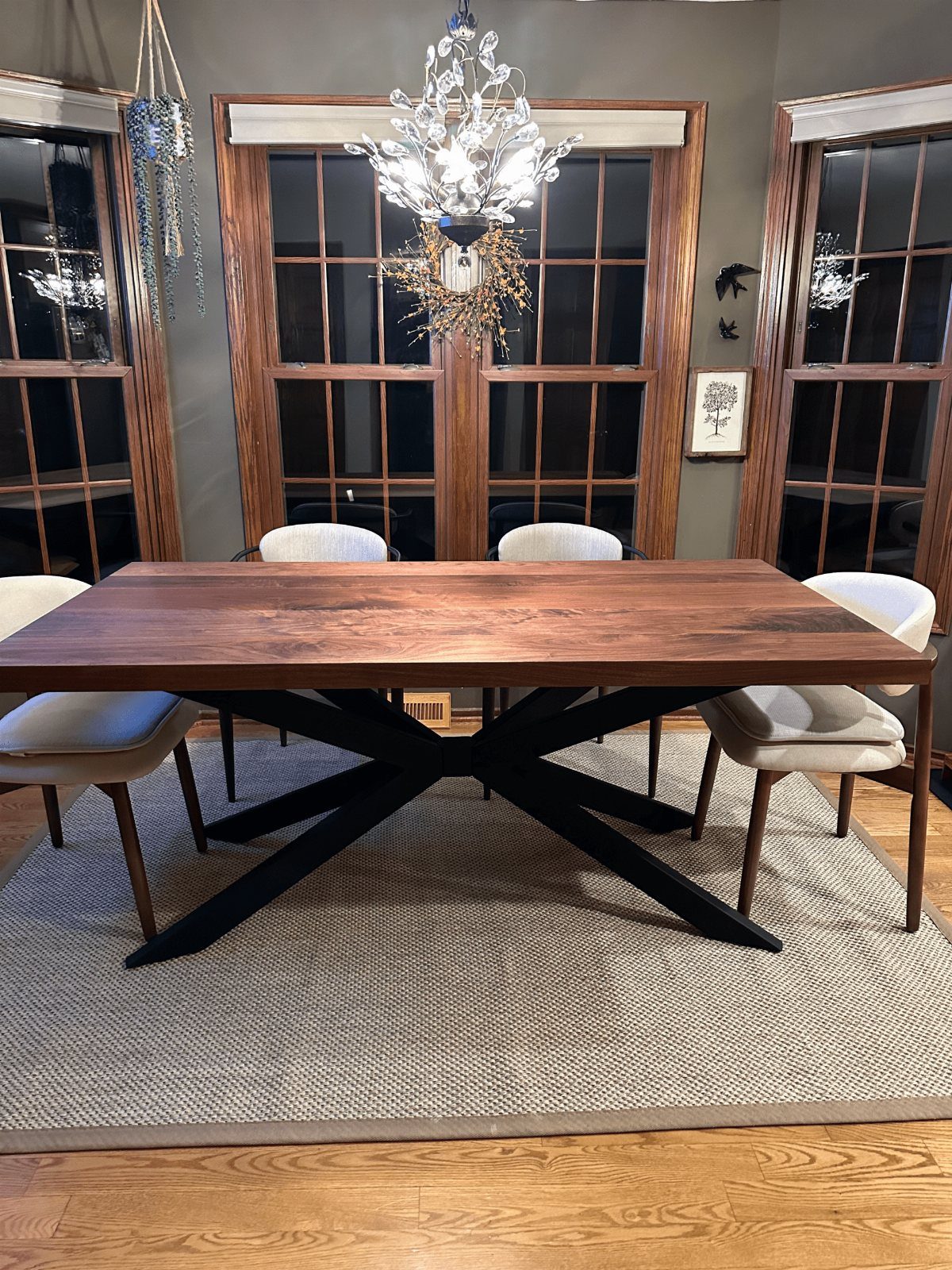 Dark wood dining table with black metal X-legs and white upholstered chairs.