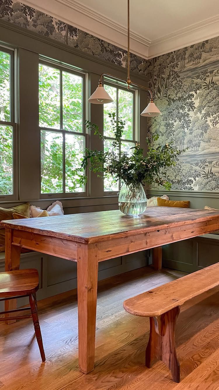 Wooden dining table and bench in a bay window nook with built-in seating.