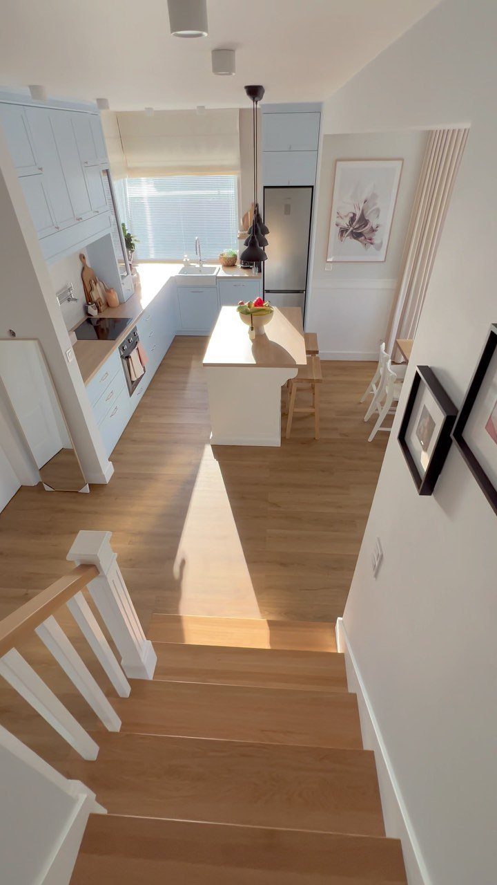 White kitchen island with wooden countertop and stools in a bright, modern kitchen.