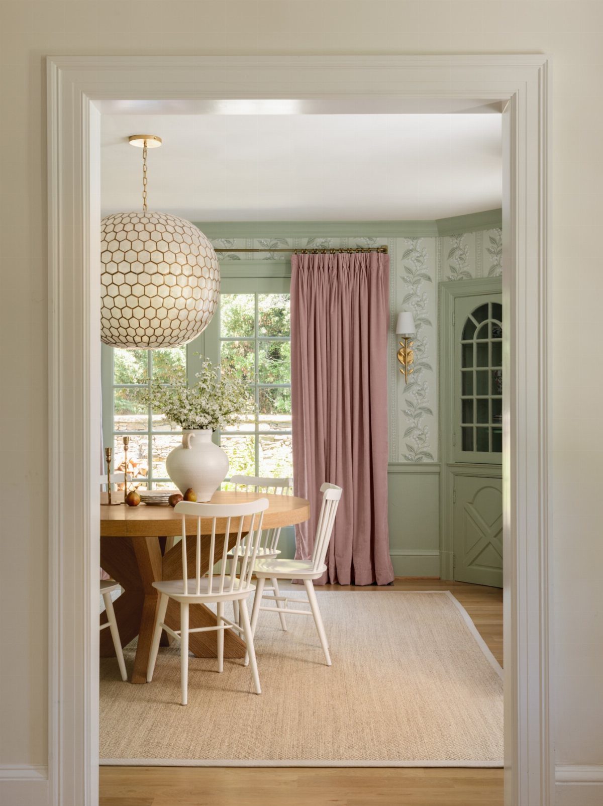 Dining area with wooden table, white chairs, and large spherical pendant light.