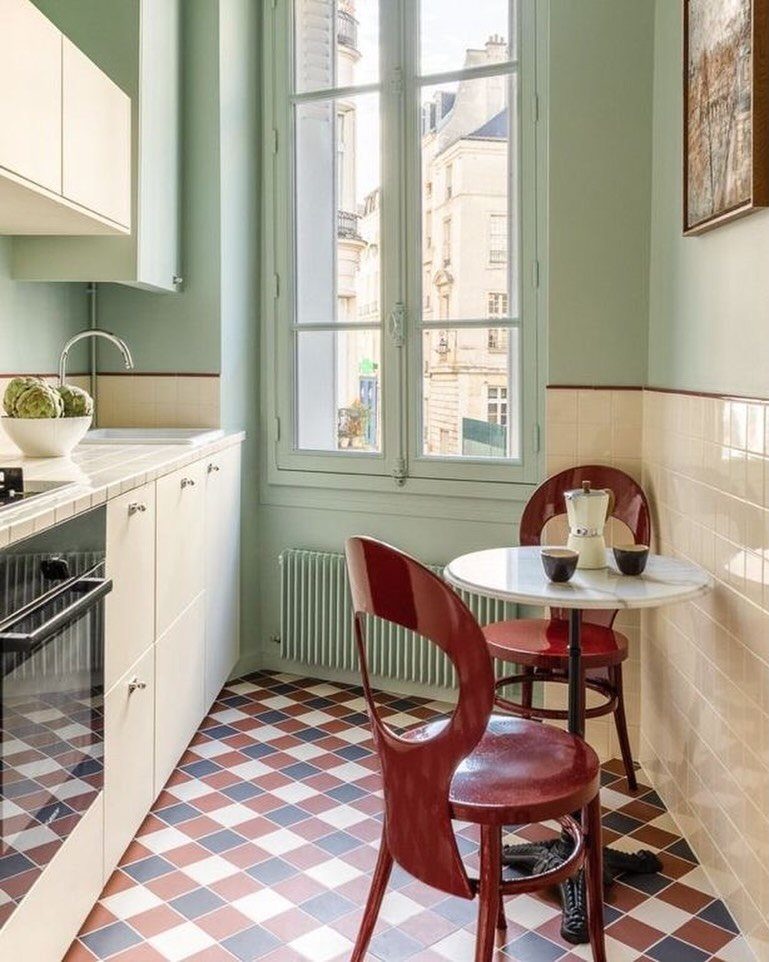 Small round white table with two red chairs in a bright kitchen