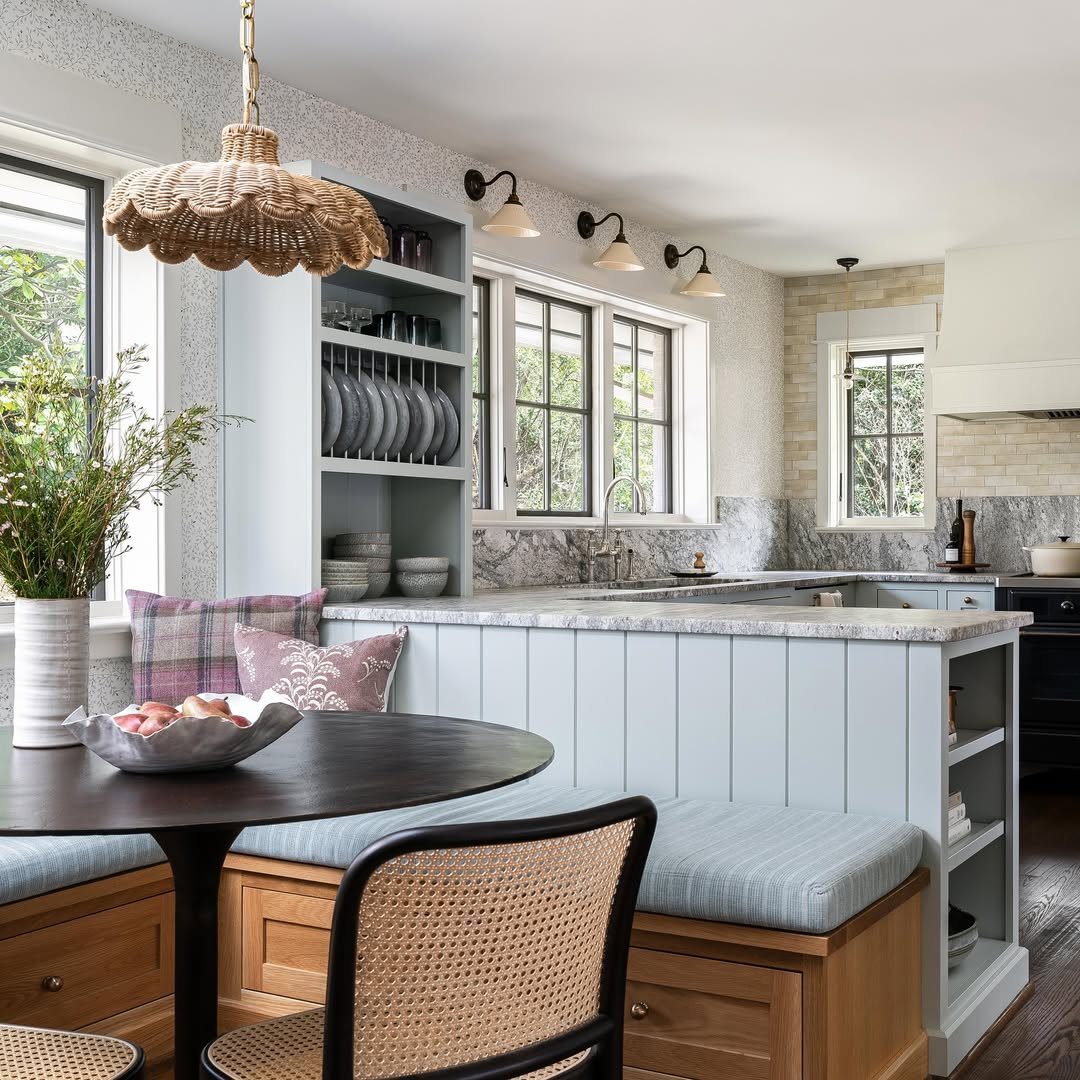 Round black dining table with built-in bench seating and a light blue kitchen hutch.